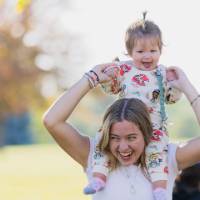 Woman holding child on her shoulders.
